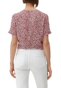 Kurzärmliges Oberteil in einem rosa und schwarzen Blumenmuster. Weicher Stoff mit legerem Schnitt, rundem Ausschnitt und leicht verkürztem Saum.