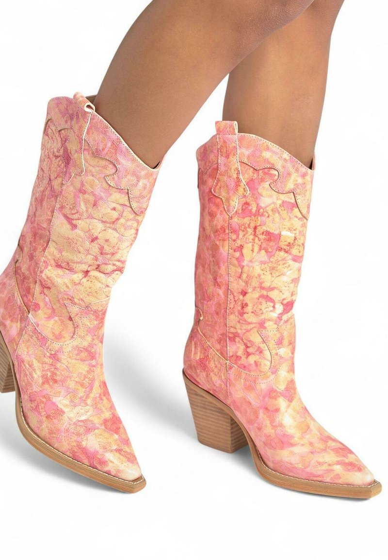 Botas de vaquero rosas con una textura veteada, puntera afilada y costuras decorativas. Presentan un tacón de madera apilada y un borde superior en forma de onda.