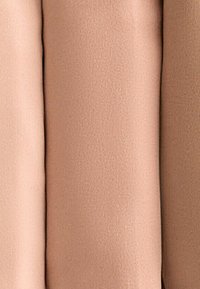 Zachte, beige stoffen secties dicht op elkaar gestapeld, met een gladde textuur en een uniforme kleur, met subtiele variaties in tint.