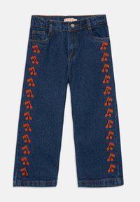 Jeans infantiles azules con cerezas bordadas en naranja corriendo verticalmente por ambas piernas, con bolsillos delanteros y cierre de botón.