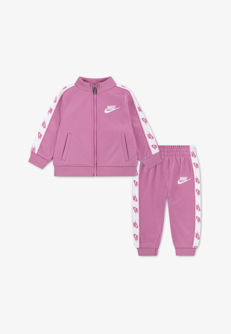 Rosa Trainingsanzug-Set mit einer Jacke mit Reißverschluss und Seitentaschen sowie passenden Hosen. Beide Teile sind mit weißen Nike-Logos und Akzenten versehen.