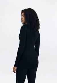 Top preto de mangas longas, feito de um tecido elegante, apresentando um design ajustado com um decote redondo e uma parte de trás ligeiramente alongada.