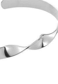 Srebrny metaliczny naszyjnik choker o gładkim, falistym wzorze, z wypolerowanymi krzywiznami i błyszczącym wykończeniem. Minimalistyczny i nowoczesny styl.