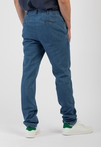 Pantaloni in denim blu con una vestibilità slim, dotati di una cintura elastica, due tasche posteriori e orli cuffati. Abbinati a sneakers bianche.