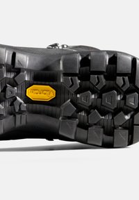 Schwarze Wanderschuhsohle mit einem robusten Profilmuster. Mit einem gelben Vibram-Logo. Strukturiertes Gummi mit multidirektionalen Stollen für optimalen Halt.