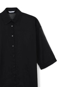 Camicetta nera a maniche corte realizzata in un materiale leggero. Presenta un colletto classico e una chiusura con bottoni frontale, con bottoni neri coordinati.