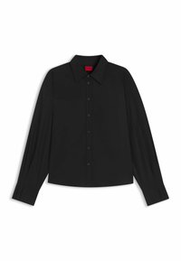 Camicia nera a maniche lunghe con bottoni, polsi larghi e colletto a punta su uno sfondo bianco.