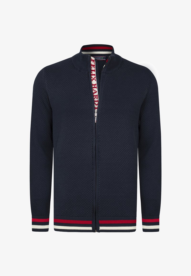 Námořnický zip-up svetr s texturovaným vzorem ve tvaru včelí plástve. Obsahuje stojatý límec a pruhované červené, bílé a námořnické ribbed akcenty na lemu a manžetách.