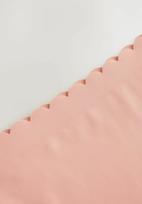 Textiel met gegolfde rand in zacht roze, met een gladde textuur en een subtiele glans, met een nette, precieze snede langs de rand.