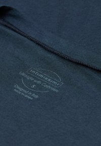 Dunkelmarineblauer Stoff mit einer weichen Textur, versehen mit aufgedruckten Etiketten, die die Größe und Materialzusammensetzung anzeigen, und einem sauberen Finish an den Nähten.
