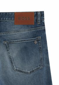 Jeans in denim blu scuro con un'etichetta in pelle con la scritta "BOSS" in vita, dotati di una tasca posteriore con un dettaglio logo cucito.