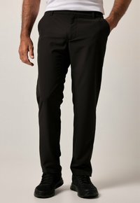 Zwarte broek van lichtgewicht stof, met een platte voorkant, recht gesneden pijpen, zijzakken en gedragen met zwarte sneakers.