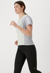 Lys grønn og grå idrettstrøye med kort erme, med tre hvite striper på skuldrene, sammen med svarte leggins.
