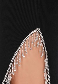 Tessuto nero a coste con dettagli a taglio, adornato da una cascata di strass trasparenti che creano un accento elegante all'orlo.