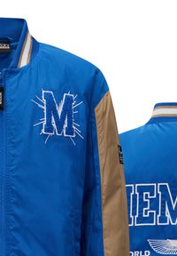 Giacca bomber blu con maniche beige, caratterizzata da un logo ricamato a forma di "M" e dettagli bianchi, chiusura a zip e colletto a costine.