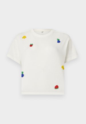 Λευκό κοντομάνικο crop top με μικρά πολύχρωμα μπιχλιμπίδια φρούτων, όπως μπανάνα, μήλο, σταφύλια και καρπούζι, διασκορπισμένα στο μπροστινό μέρος.