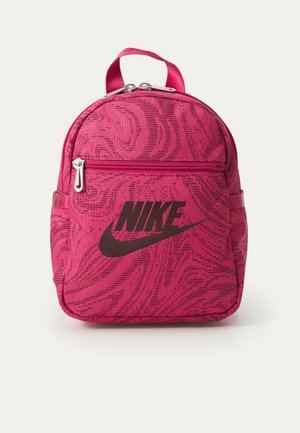 Roza tkaninska nahrbtnik z zaobljeno obliko, ki ima diskreten vzorec, sprednjo zadrgo in črn Nike logotip na sprednji strani.
