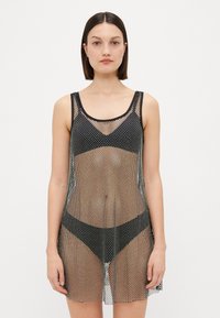 Copertura in rete nera con design senza maniche, dotata di un motivo a pois e una texture leggermente trasparente, che arriva a metà coscia.