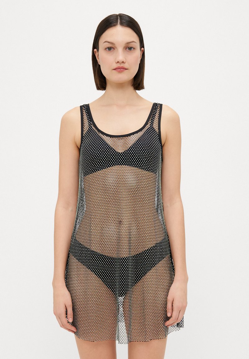 Copertura in rete nera con design senza maniche, dotata di un motivo a pois e una texture leggermente trasparente, che arriva a metà coscia.