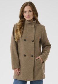 Braune, doppelt-knopflose Jacke mit hohem Kragen, Knopfakzenten und Seitentaschen; aus einem strukturierten, warmen Stoff gefertigt.