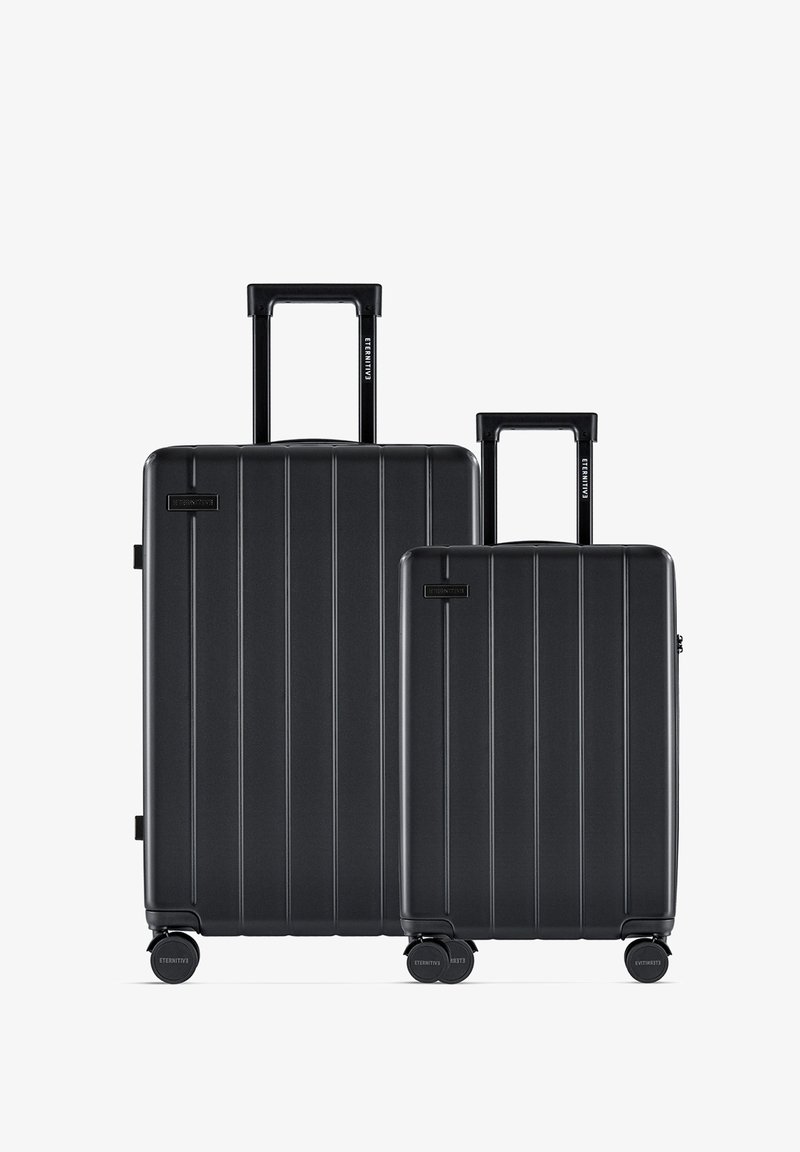 Zwart harde kofferset met verticale ribbels, bestaande uit twee maten. Beide hebben uitschuifbare handgrepen en soepel rollende wielen.