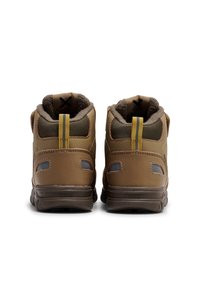 Brune ankelstøvler med tekstureret overdel, polstret krave og gul accentløkke. Har forstærket hæl og gummisål for holdbarhed.