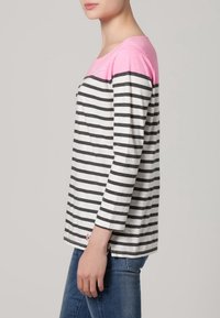 Striped long-sleeve top with grey and black horizontal stripes, pink shoulders, and embroidered detail. Cotton material, relaxed fit.