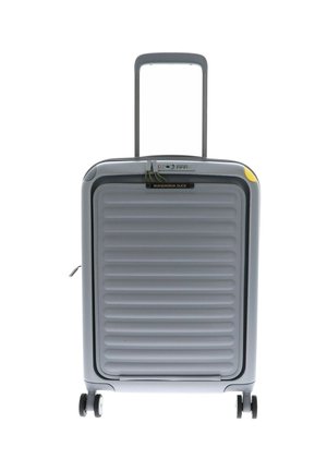 Valise rigide grise avec texture nervurée, poignée rétractable et quatre roues. Équipée d'un cadenas à combinaison et d'une étiquette de marque.