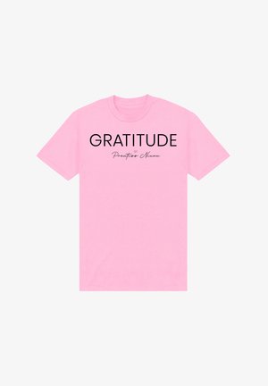 Maglietta rosa a maniche corte con testo nero "GRATITUDE by Prentiss Nixon" centrato sul petto.