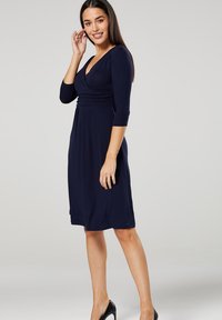 Navy blue, knee-length dress with three-quarter sleeves and a wrap front design. Smooth fabric with subtle draping at the waist.