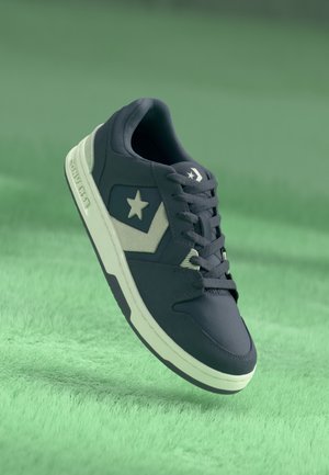 Tumesin sneaker valge tähe ja aktsentidega, millel on sile tekstiilpealis ja kummist tallad. Kujundatud igapäevaseks kandmiseks, seotud nööridega.