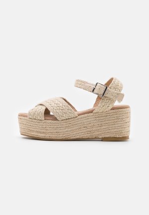 Vævede beige platform-sandaler med krydsede remme, justerbar ankelspænde og tekstureret jute-detalje på kilehælen.