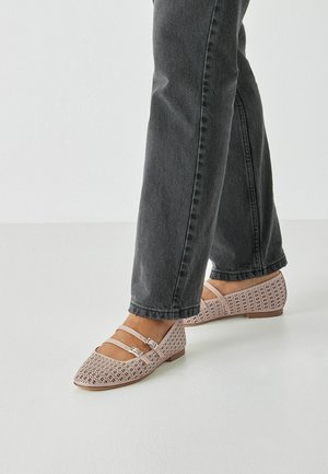 Flache Schuhe mit hellrosa perforiertem Design, spitzer Zehenpartie und zwei schmalen Knöchelriemen. Obermaterial aus strukturiertem Leder und eine flache, niedrige Sohle.