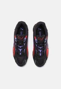 Zapatos deportivos negros con material de malla y acentos en rojo y púrpura, superficies texturizadas, suela acolchada y cordones en contraste.