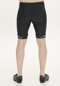 Pantalones cortos de ciclismo negros con inserto acolchado, material de nylon suave y logo blanco de "ENDURANCE" contrastante en las piernas inferiores.