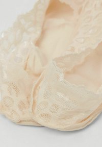 Lencería de encaje beige con una textura suave, que presenta intrincados patrones florales y bordes festoneados, diseñada para ofrecer comodidad y un ajuste ceñido.