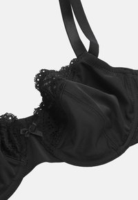 Zwarte bh met kantdetails, voorgevormde cups en satijnen accenten. Voorzien van verstelbare bandjes en een vrouwelijke strikdetail in het midden.