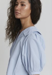 Camicia a maniche puff leggermente blu, realizzata in cotone testurizzato, con colletto classico e una vestibilità leggermente rilassata.