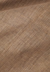 Tissu tissé brun avec une surface texturée, présentant un motif subtil et des détails de couture visibles, créant une apparence chaleureuse.