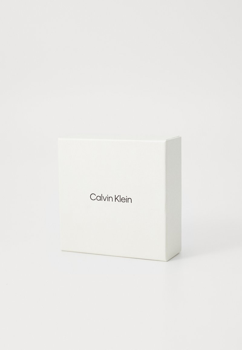 Boîte rectangulaire blanche avec "Calvin Klein" imprimé en noir au centre sur le devant, sur fond blanc uni.