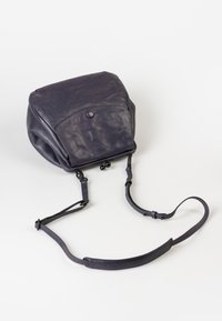 Zaino in pelle di un viola scuro con forma arrotondata. Presenta un flap anteriore, chiusura magnetica e spallacci regolabili. Texture liscia.