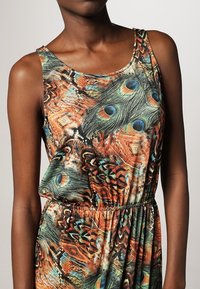 Robe sans manches avec un motif de plumes de paon colorées dans des teintes d'orange, de vert et de bleu, dotée d'une taille élastique et d'une texture de tissu douce.