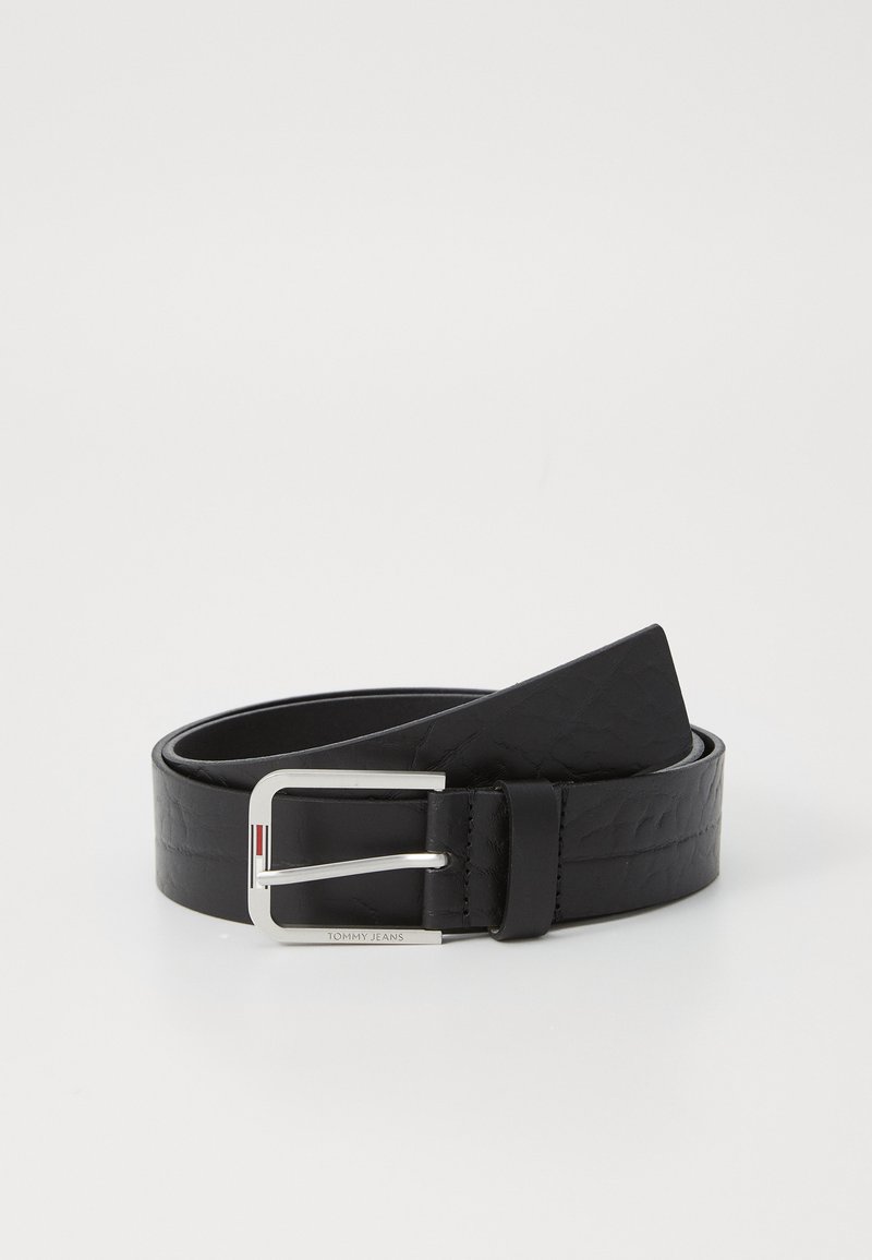 Cinturón de cuero negro con una hebilla de metal plateado, que presenta una textura suave y una forma rectangular. Incluye un detalle de marca en la hebilla.