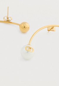 Kuldne rõngastelged, üks sileda kuldse palliga ja teine valgest pärlist ning väikese kuldse dekoratiivse klambriga.