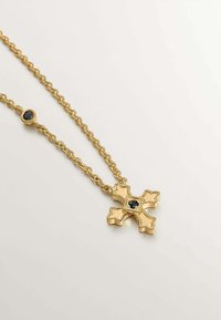 Collar de cadena de oro con un colgante de cruz ornamentada que cuenta con una piedra negra en el centro y una piedra negra a juego en la cadena.