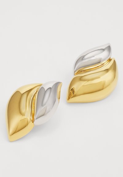 Boucles d'oreilles en forme de feuilles en or et en argent, présentant une texture lisse, une finition polie et un design contemporain avec une courbe élégante.