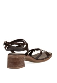 Sandalias de tacón abiertas de color marrón con diseño de tiras cruzadas. Parte superior de piel texturizada, tacón cuadrado con patrón de vetas de madera, suela de goma.