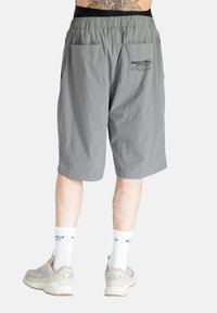 Šedé kraťasy s elastickým pasem, dvěma bočními kapsami a dvěma zadními kapsami. Na zadní straně je potisk "MULTIPLY APPAREL". Vyrobeno z lehkého materiálu.
