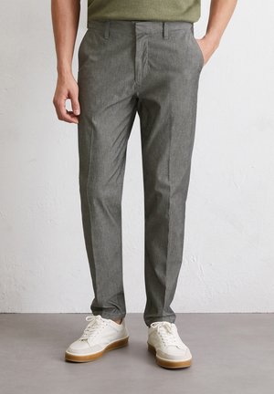 Grijze, gestructureerde broeken met een getailleerde pasvorm, met een vlakke voorkant, riemlussen en zijzakken, gecombineerd met witte sneakers.