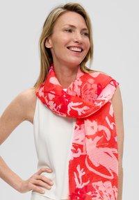 Écharpe florale rouge avec un design texturé et côtelé. Présente des motifs floraux abstraits en rose et blanc, en tissu léger, drapée élégamment.